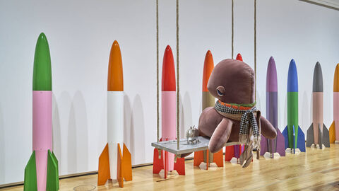 C.v. Bonin / Wie fühlen sich Raketen an? Wie fühlen sich Raketen an? Aufgereihte bunte Raketen und ein riesiges Plüschtier auf einer Schaukel.
