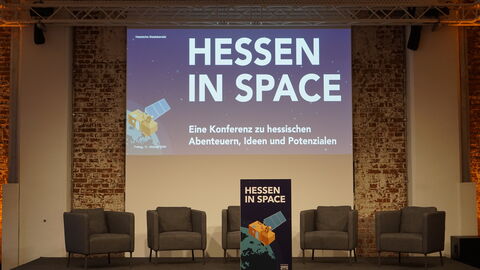 Stage for the speaker Bühne mit fünf Sessel und dem Veranstaltungsbanner im Hintergrund